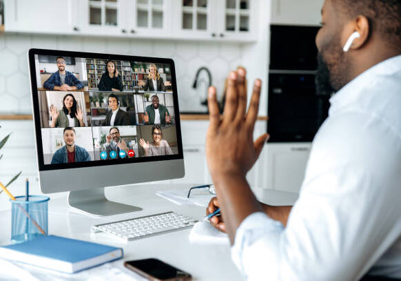 Video call, online conference. Over shoulder view of african american man at computer screen with multinational group of successful business people, virtual business meeting, work from home concept