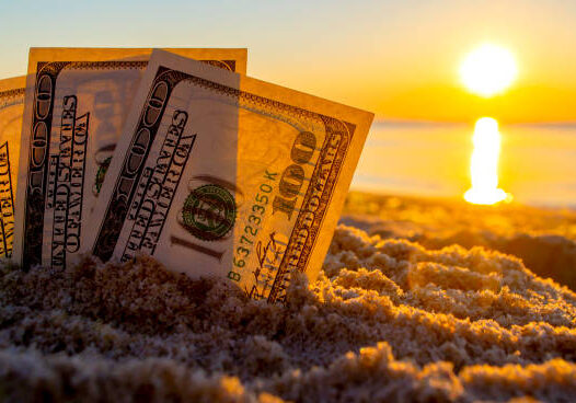 Three dollar bills are buried in sand on sandy beach near sea at sunset dawn in summer close-up. Money. Dollars covered sand. Money grows in ground. Finance and investment concept.