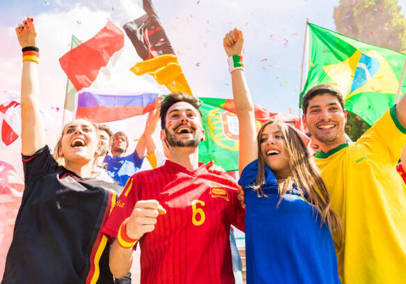 Happy supporters from different countries together at stadium. Fans from France, Germany, Spain, Brazil and other countries enjoying a match together. Sport, achievement and success concepts